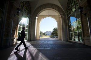 Student walking through the student center archway on a sunny day