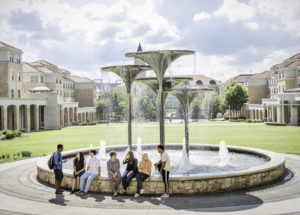 Students hanging out by Frog Fountain in the Campus Commons on a sunny day