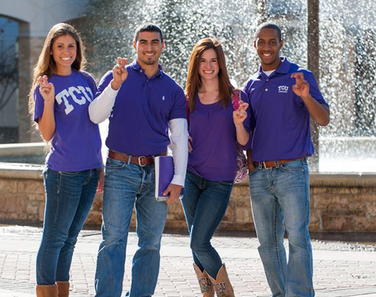 Four TCU students making handsign posing in front of Frog Fountain
